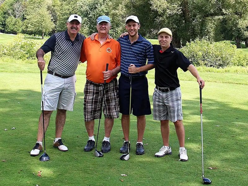 Four men are posing for a picture on the golf course.