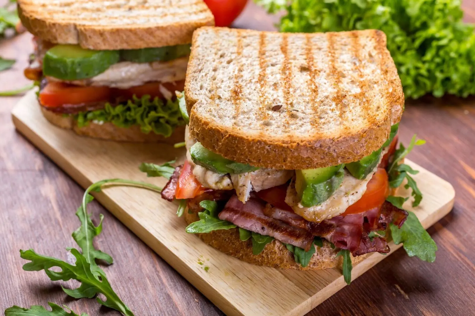 A sandwich cut in half on top of a wooden board.