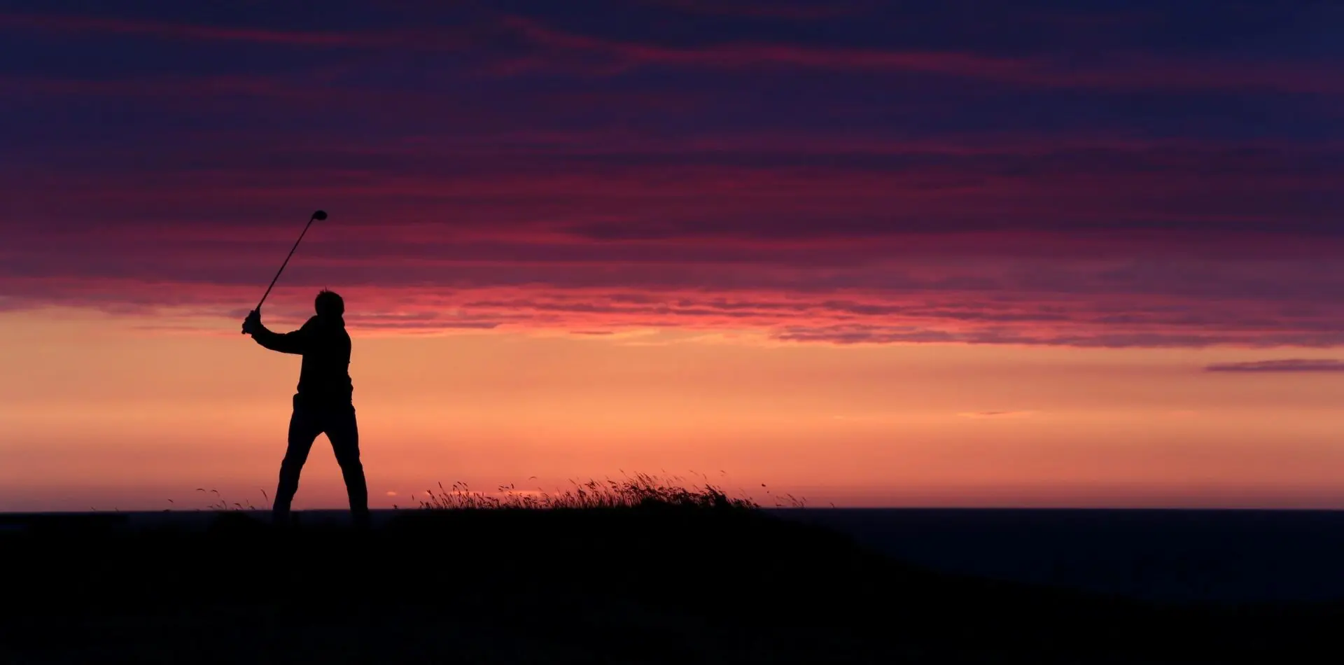 A person standing on top of a hill at sunset.